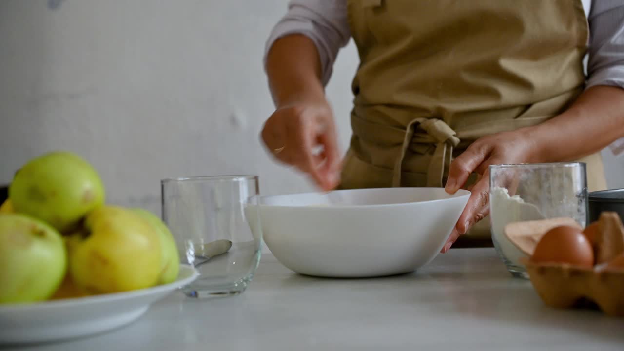 面包师在碗里搅拌配料，青苹果、鸡蛋和面粉放在桌子上视频素材