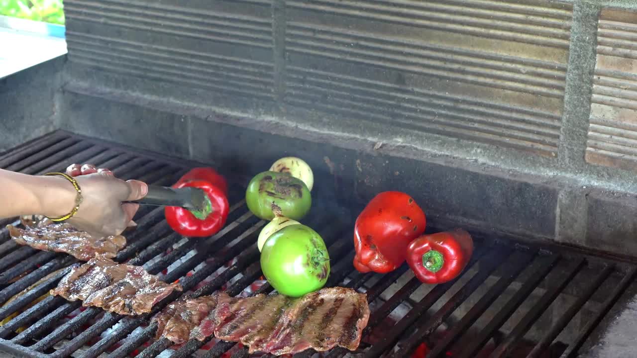 在烤架上用手烤红青椒和牛肉条。视频素材