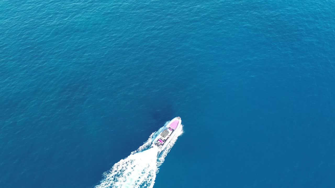 在夏季日落时，一艘无人驾驶摩托艇在广阔的蓝色海洋中漂流的航拍照片视频下载