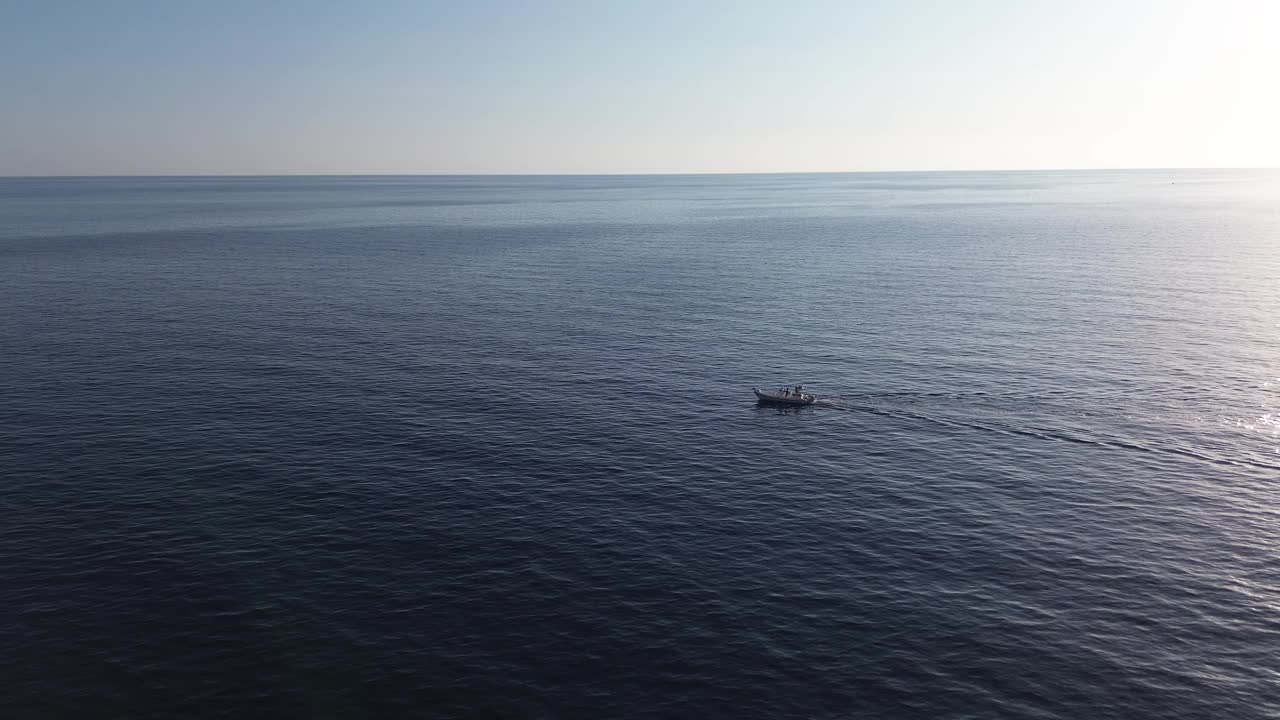 在夏季日落时，一艘无人驾驶摩托艇在广阔的蓝色海洋中漂流的航拍电影视频下载