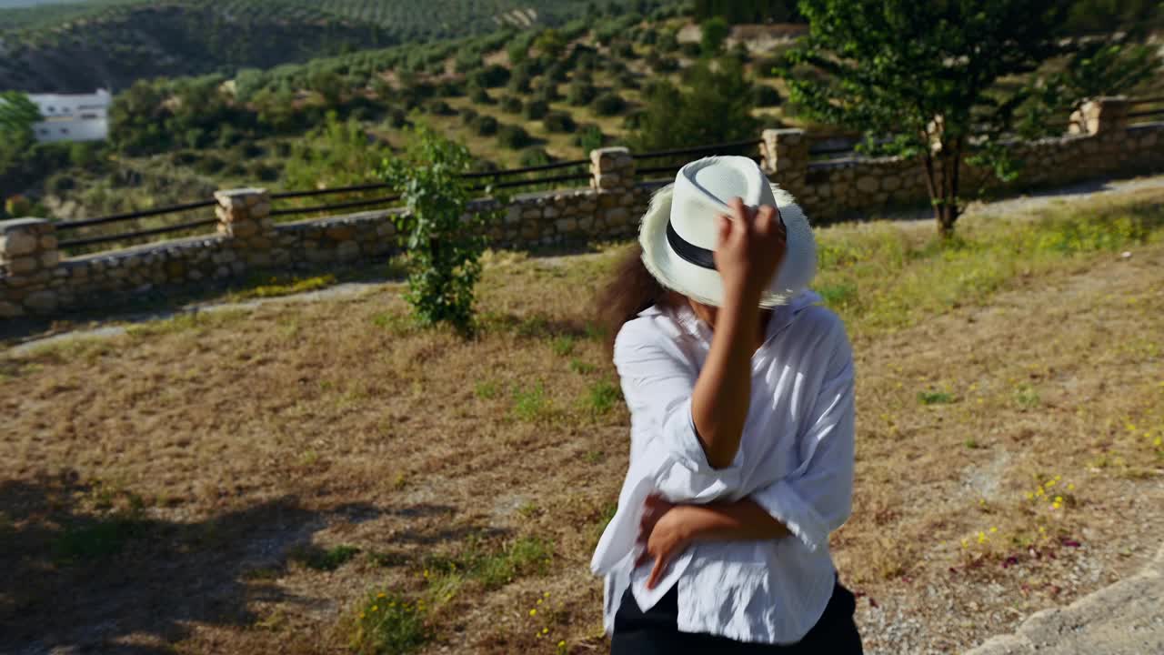 一个女人在宁静的乡村风景中跳舞，有树和山，享受自然和自由视频素材