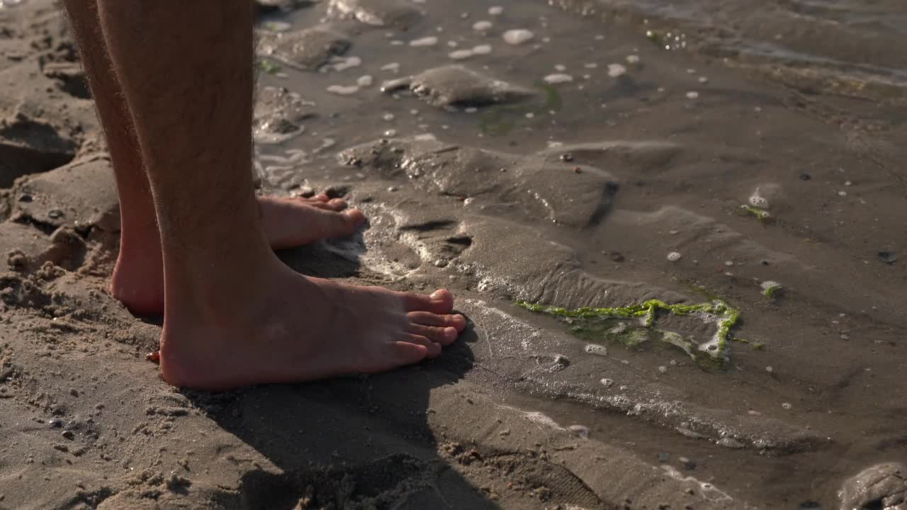 海水涌到了站在沙滩上的那个人的脚边。视频素材