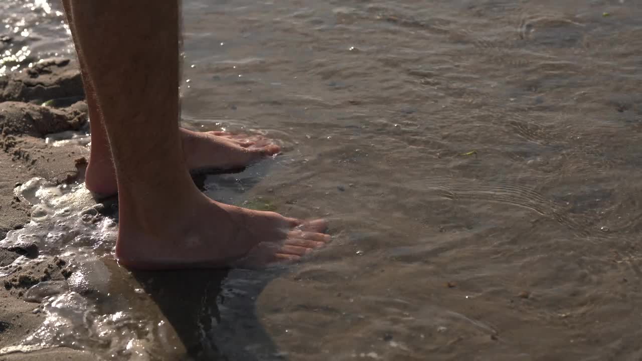 海水涌到了站在沙滩上的那个人的脚边。视频素材