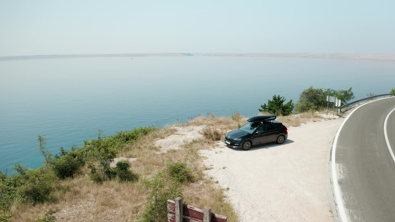 汽车车顶箱停放在公路附近的悬崖对蔚蓝的大海视频素材