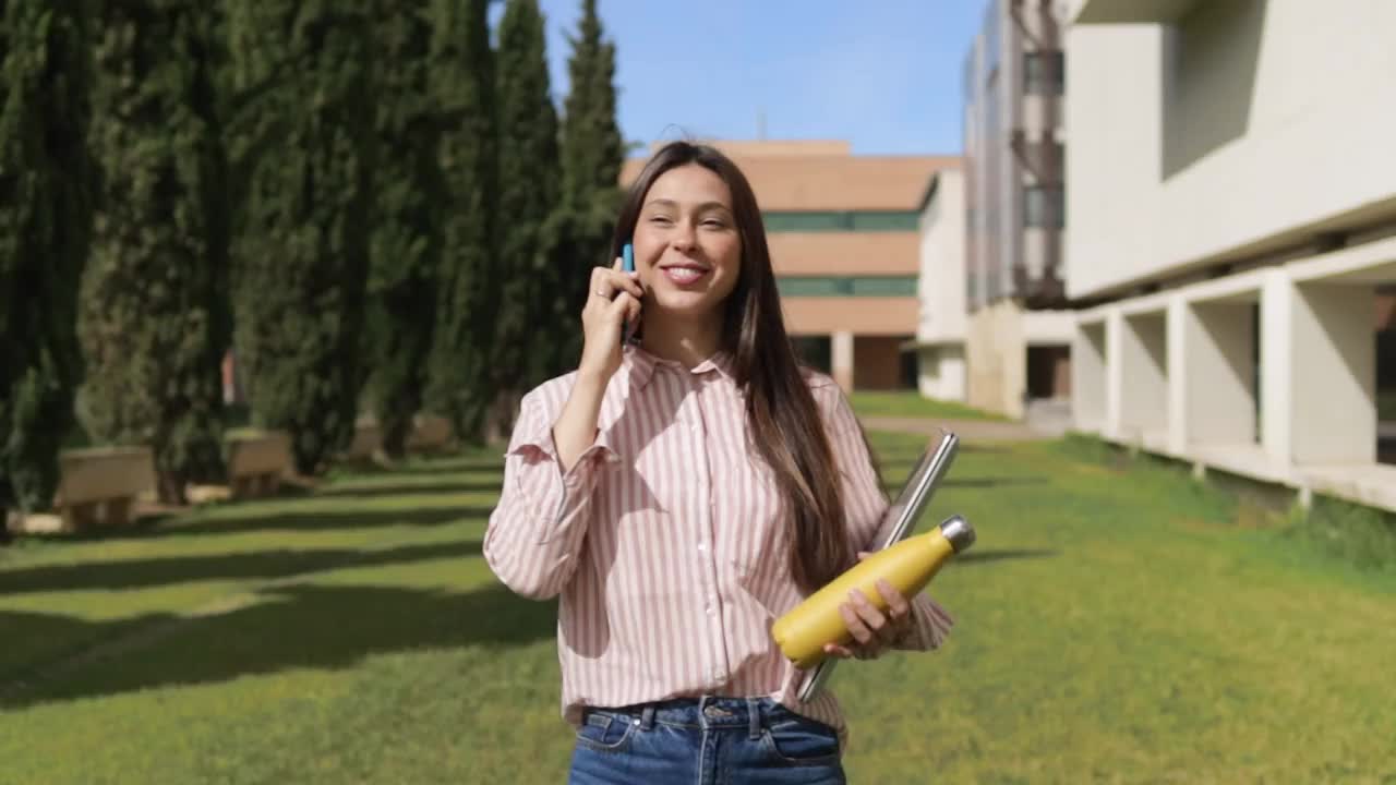 漂亮的大学生在大学校园里打电话和散步。视频素材