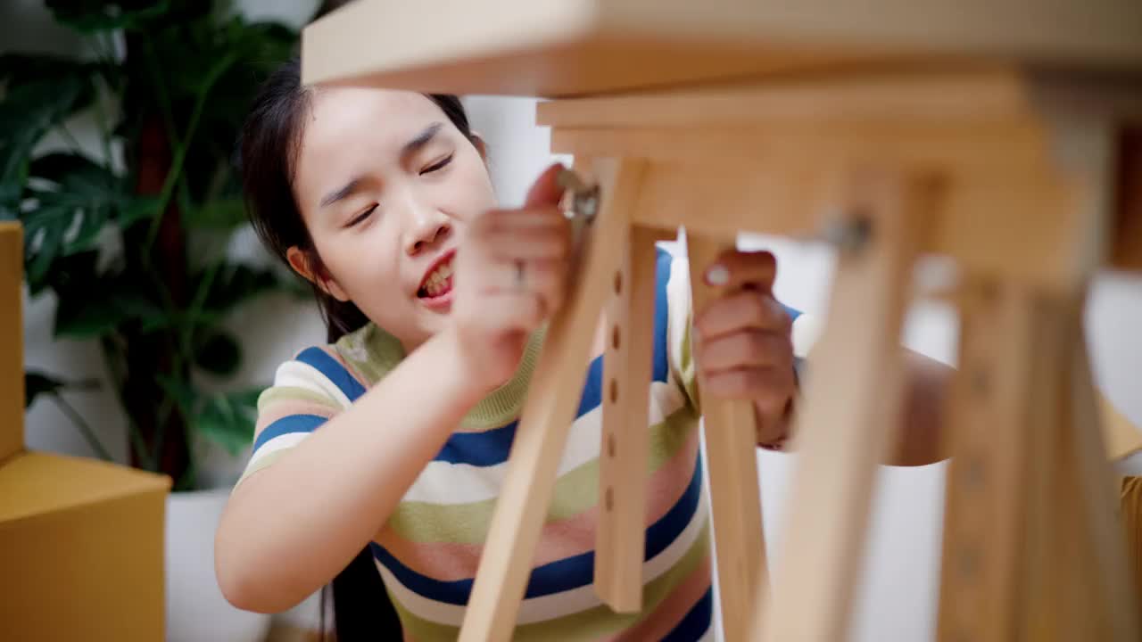 年轻女子正在家里组装家具。视频素材