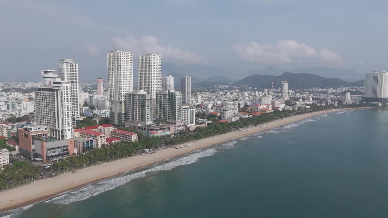 这是芽庄天际线的动态鸟瞰图，滚滚的云层勾勒出城市景观，而车流优雅地穿过下面熙熙攘攘的街道。视频素材