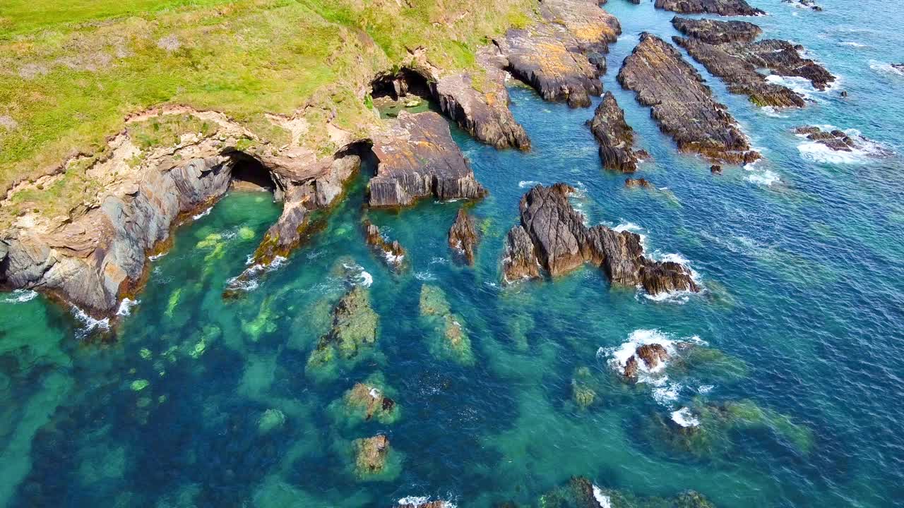 海洋平静地休息着，它的表面在锯齿状岩石的锋利衬托下平滑。水面闪烁着蓝色的光芒。视频素材