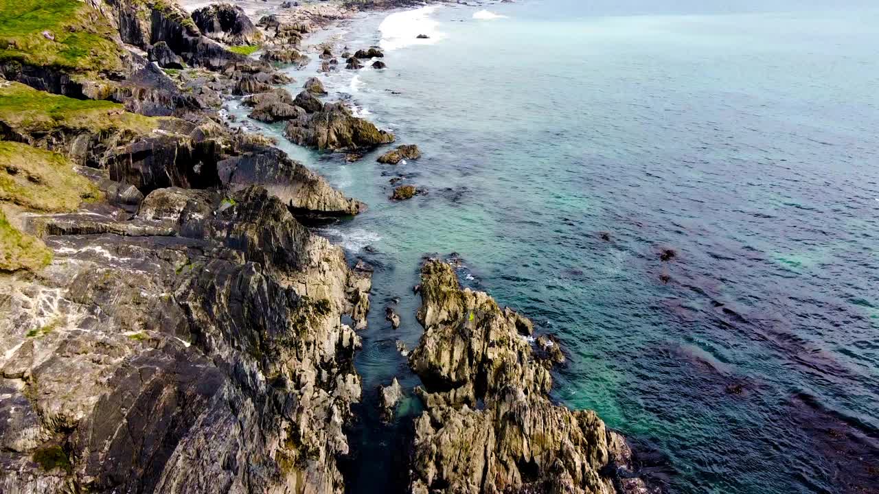 大海很平静，岩石散布在海岸线上。水呈现出浓郁的蓝色。视频素材