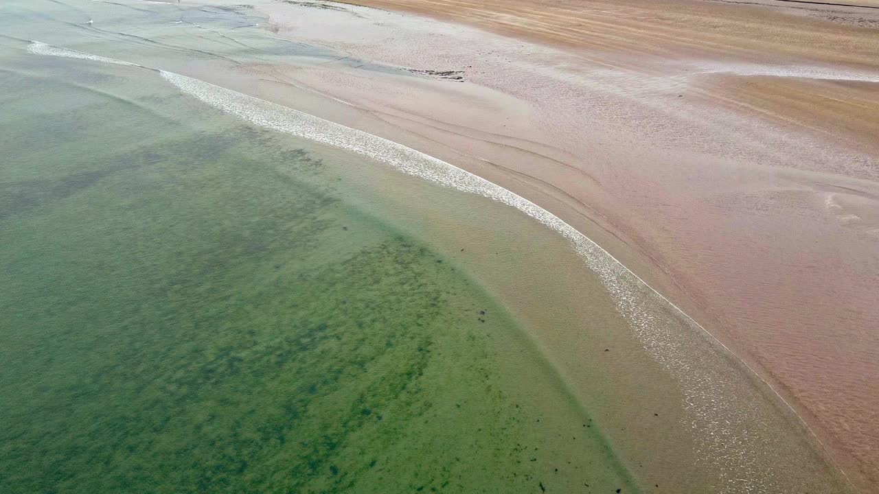 有波浪和沙子的水体。海水似乎很平静，沙子散落在整个地区。当海浪轻轻地拍打着海岸时，景色平静而宁静。视频素材