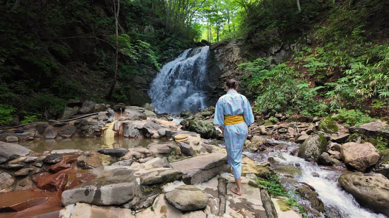 女游客在大自然中坐在室外温泉旁视频素材