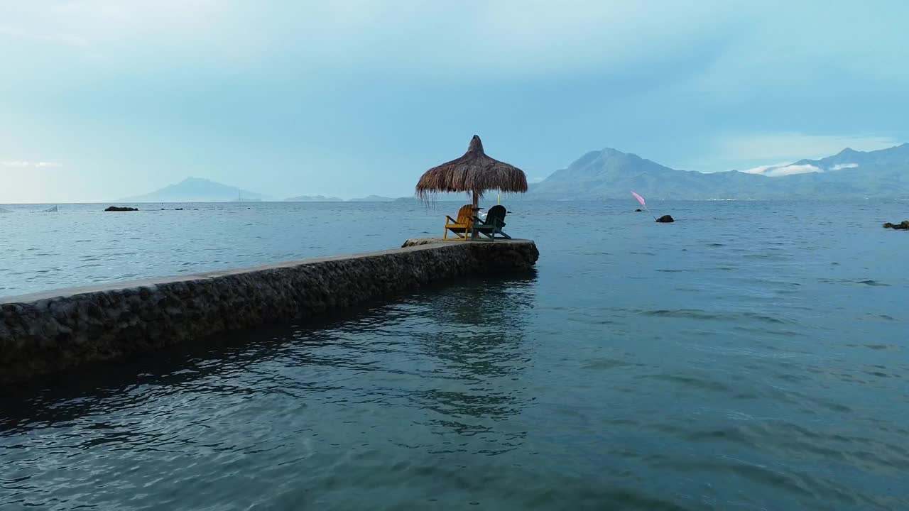 鸟瞰热带风景，海中央的凉亭、帐篷、棕榈叶屋顶的沙滩伞视频下载