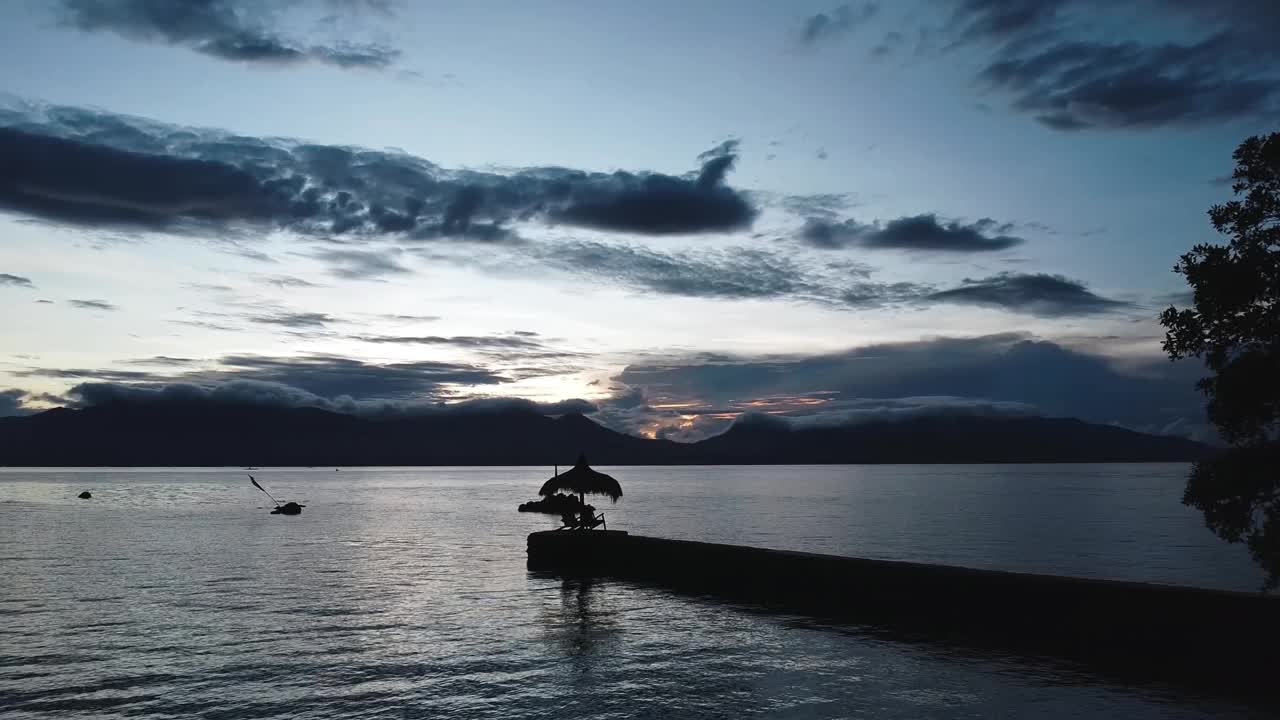 航拍的热带风景露台与棕榈叶屋顶在大海中间，黎明视频素材