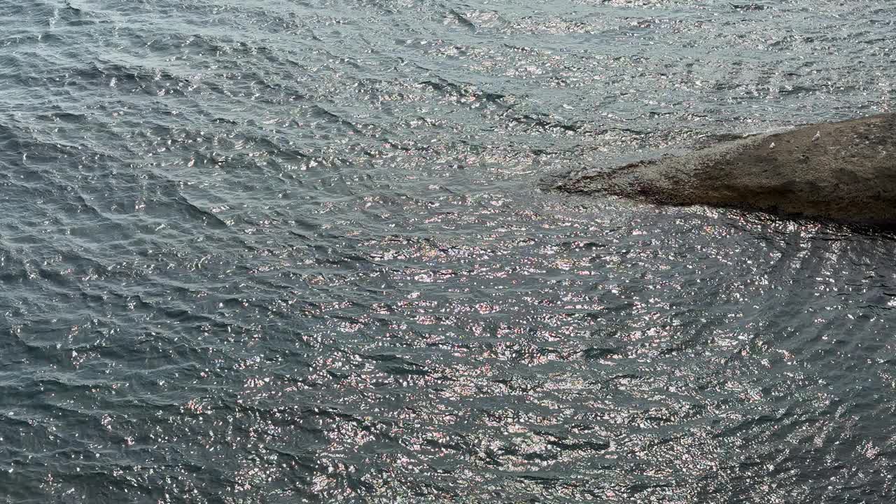 海洋闪闪发光的水涟漪和海岸岩石。视频素材