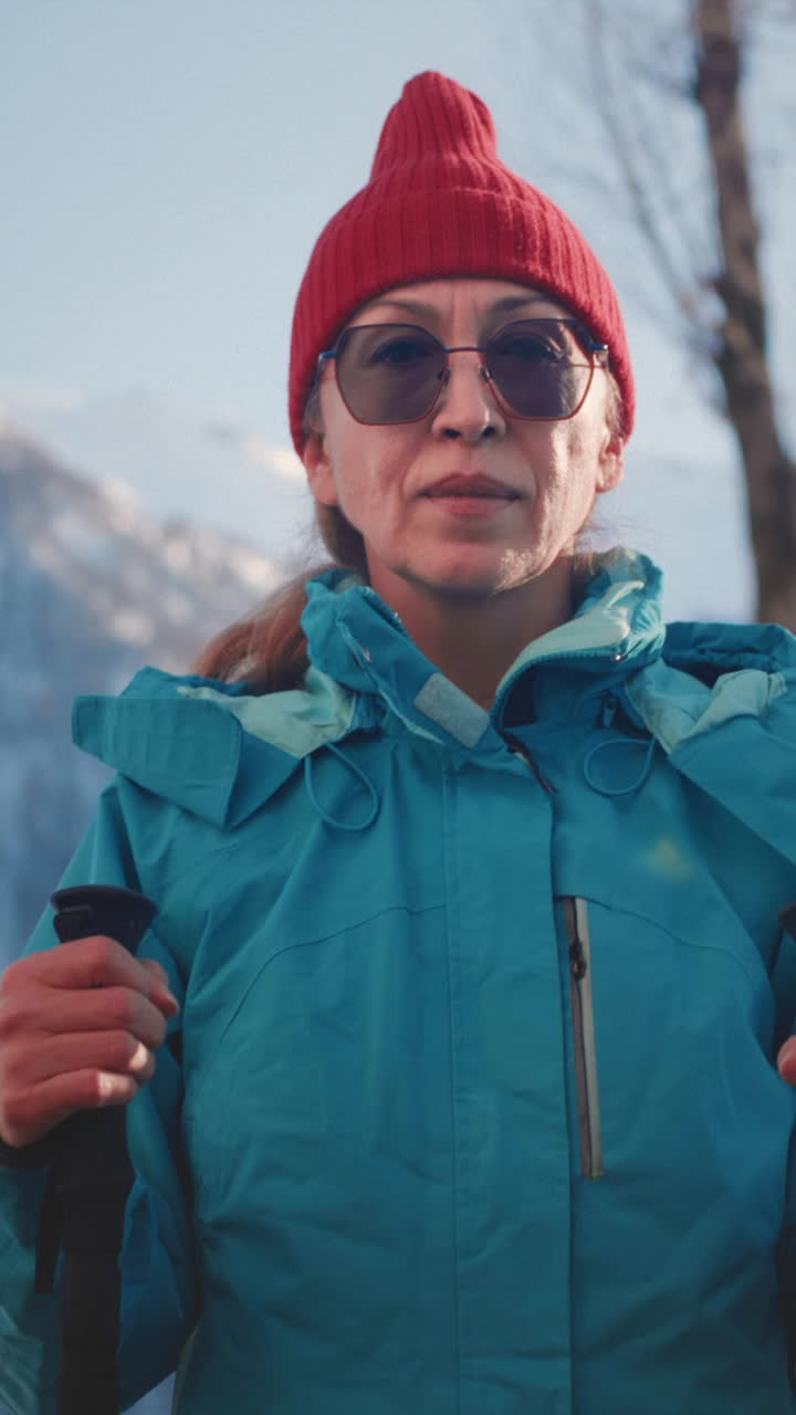 在冬天的山上徒步旅行的老妇人。一位老妇人拄着拐杖进行越野行走。白雪皑皑的山峰。视频下载