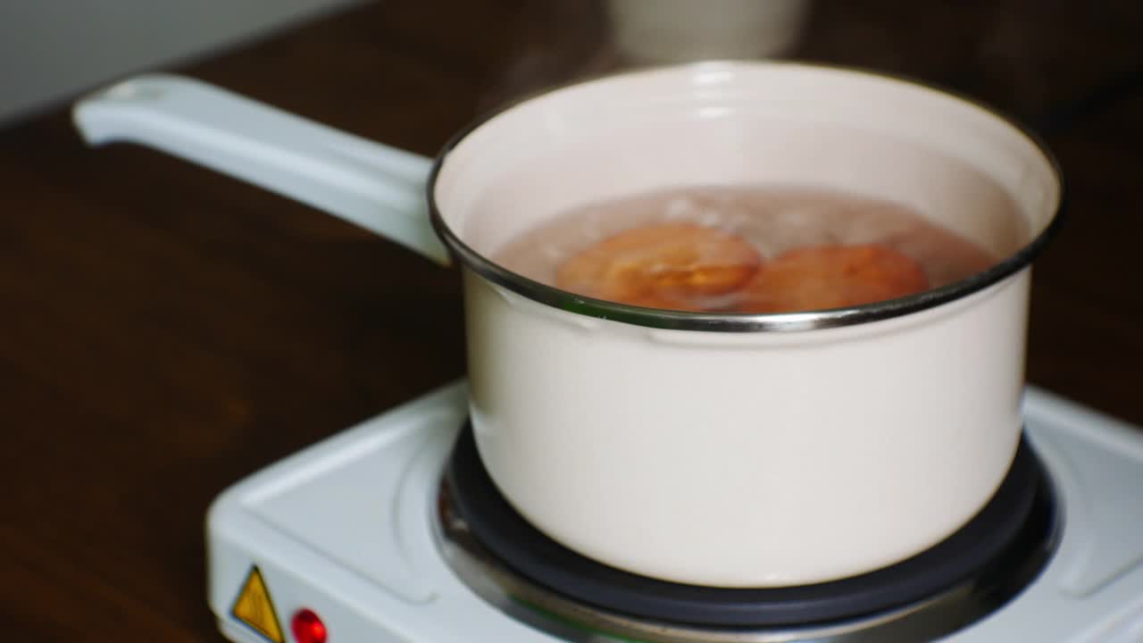 用有机鸡蛋和最少的食物准备早餐。高蛋白饮食。侧面电影特写视图。鸡蛋在小型电炉上用小搪瓷勺煮熟视频素材