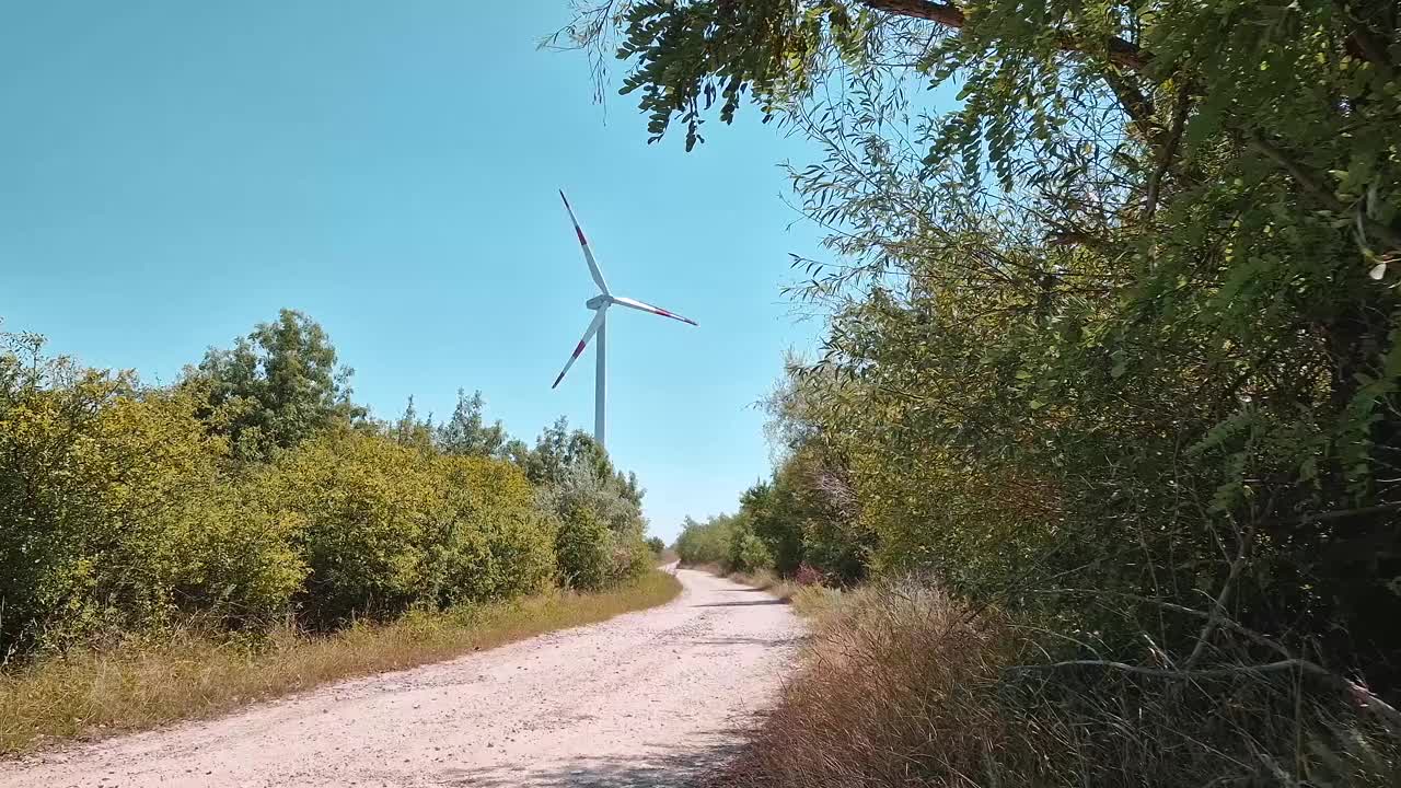 乡村道路附近的一个风力涡轮机的乡村景色。绿色节能环保理念视频下载