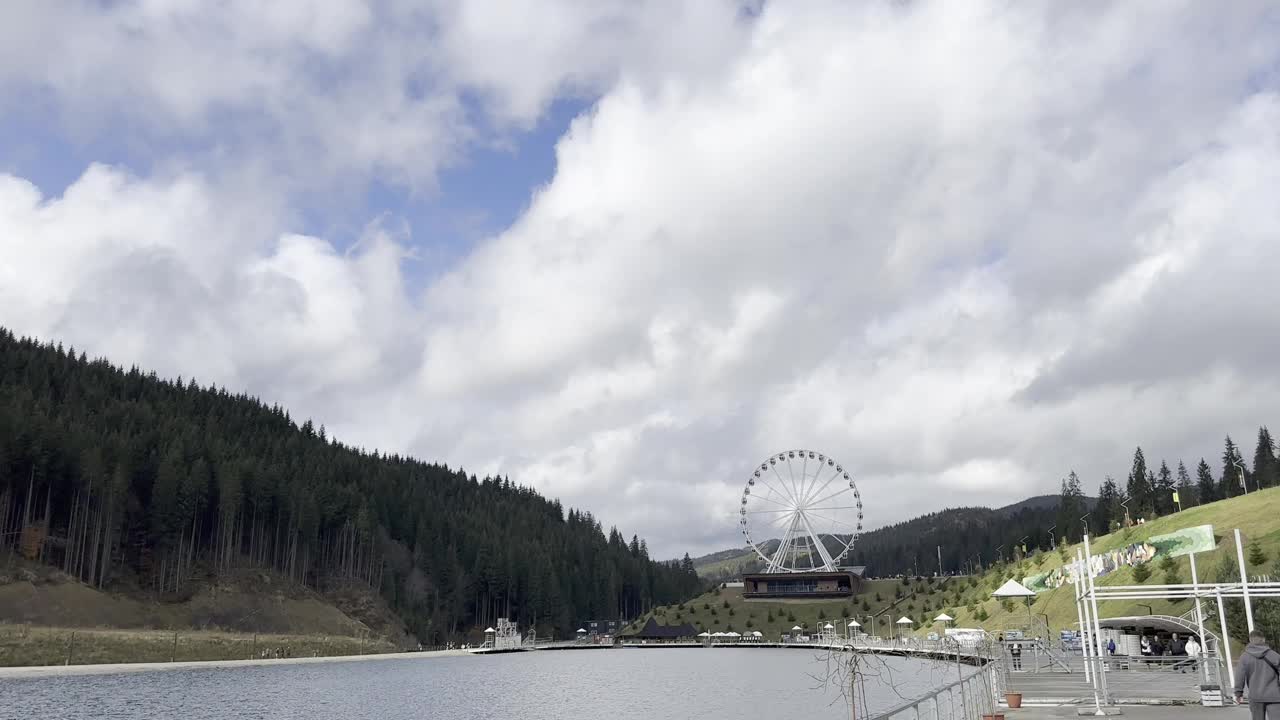 风景秀丽的湖滨景色，摩天轮和森林丘陵视频下载