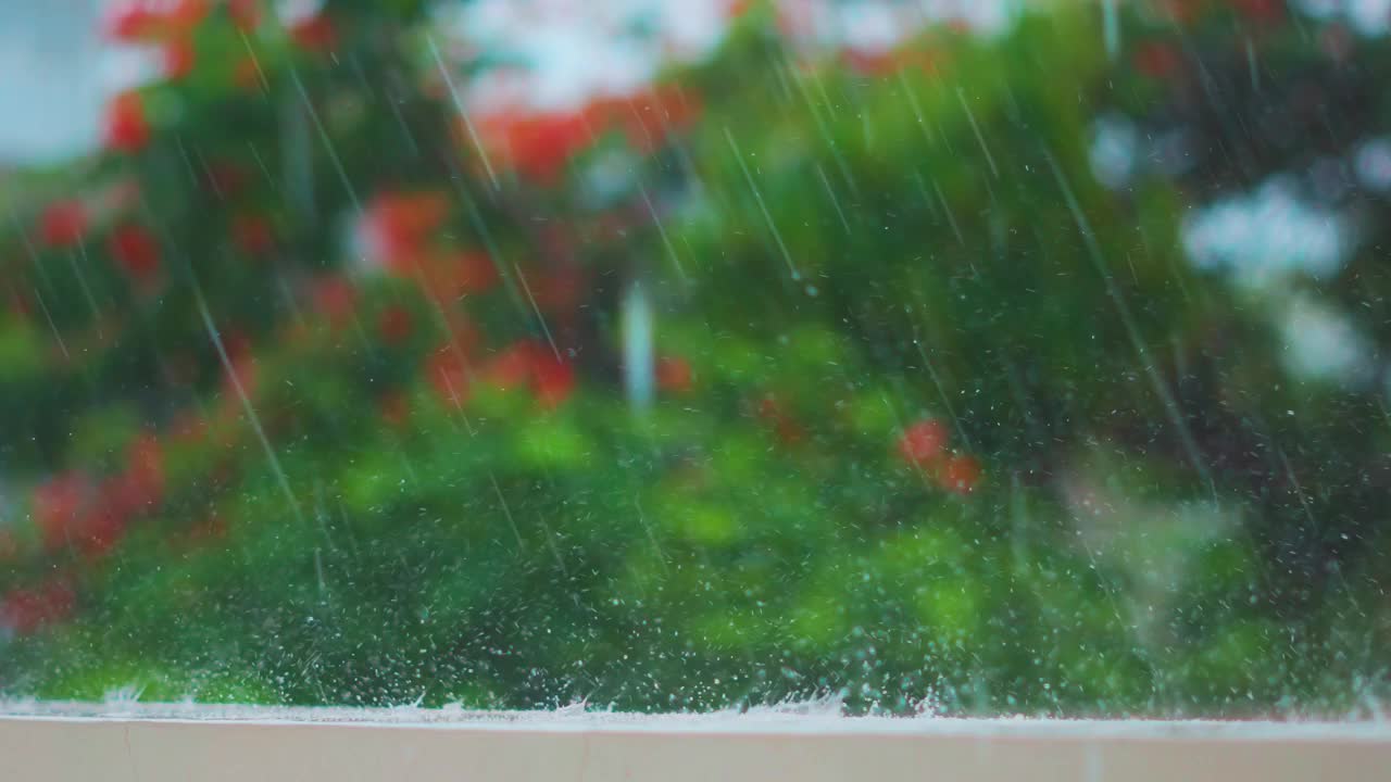 季风季节，大雨落在墙上。雨滴映衬着绿树的背景。自然背景。雨滴溅落在地板上。视频下载