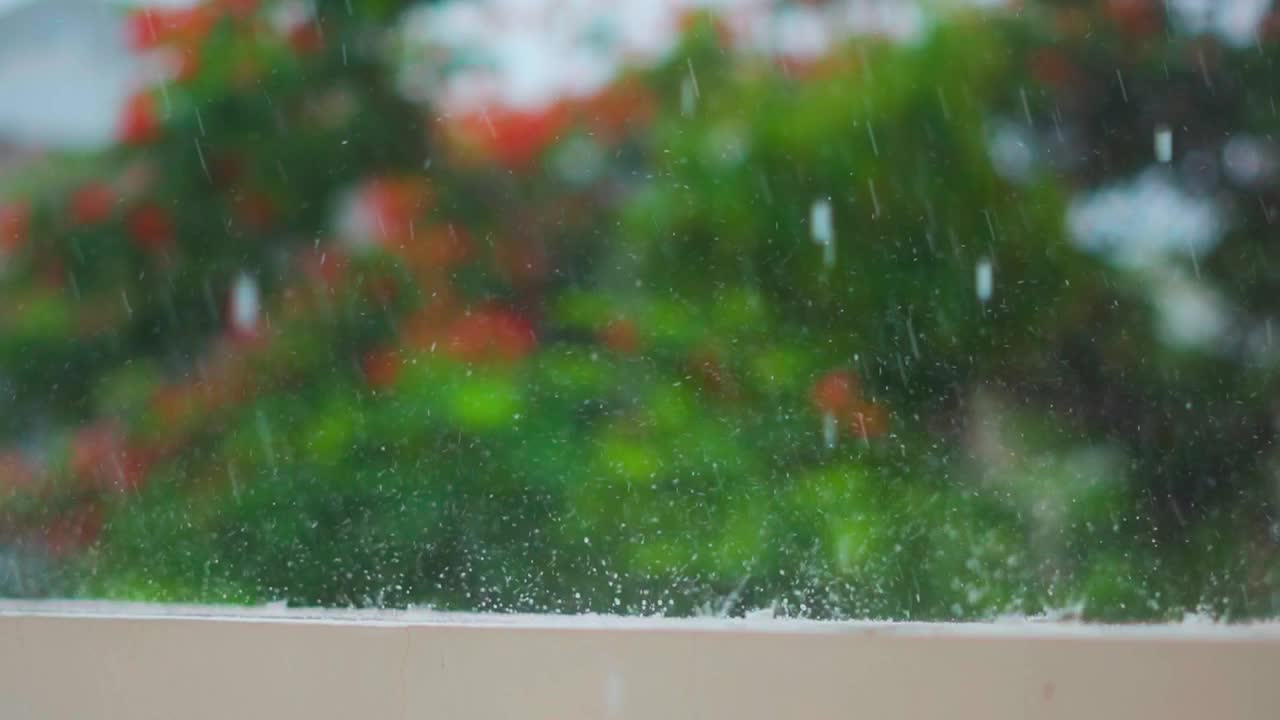 季风季节，大雨落在墙上。雨滴映衬着绿树的背景。自然背景。雨滴溅落在地板上。视频素材