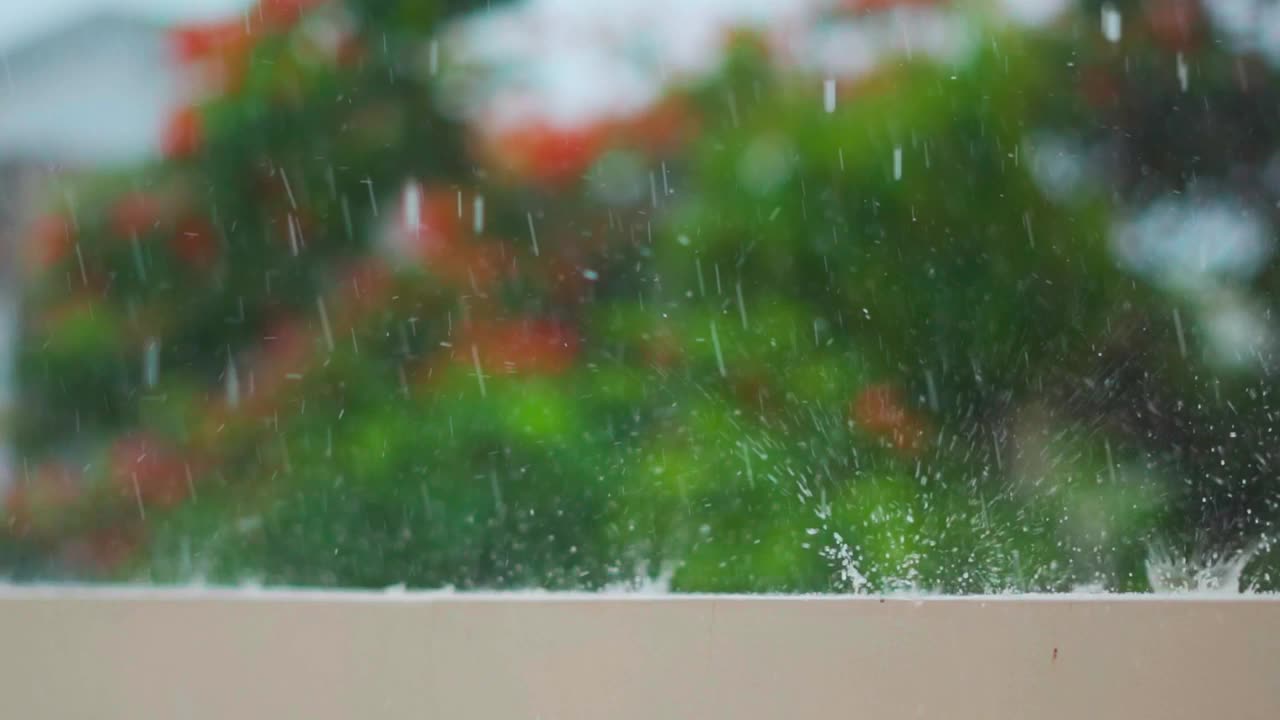 季风季节，大雨落在墙上。雨滴映衬着绿树的背景。自然背景。雨滴溅落在地板上。视频素材