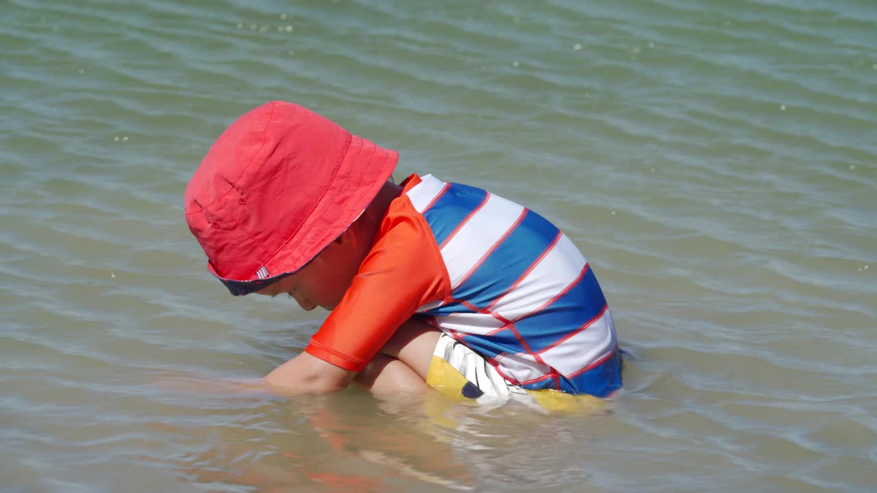 夏日里，穿着防晒服的小孩在湖边玩耍。视频素材