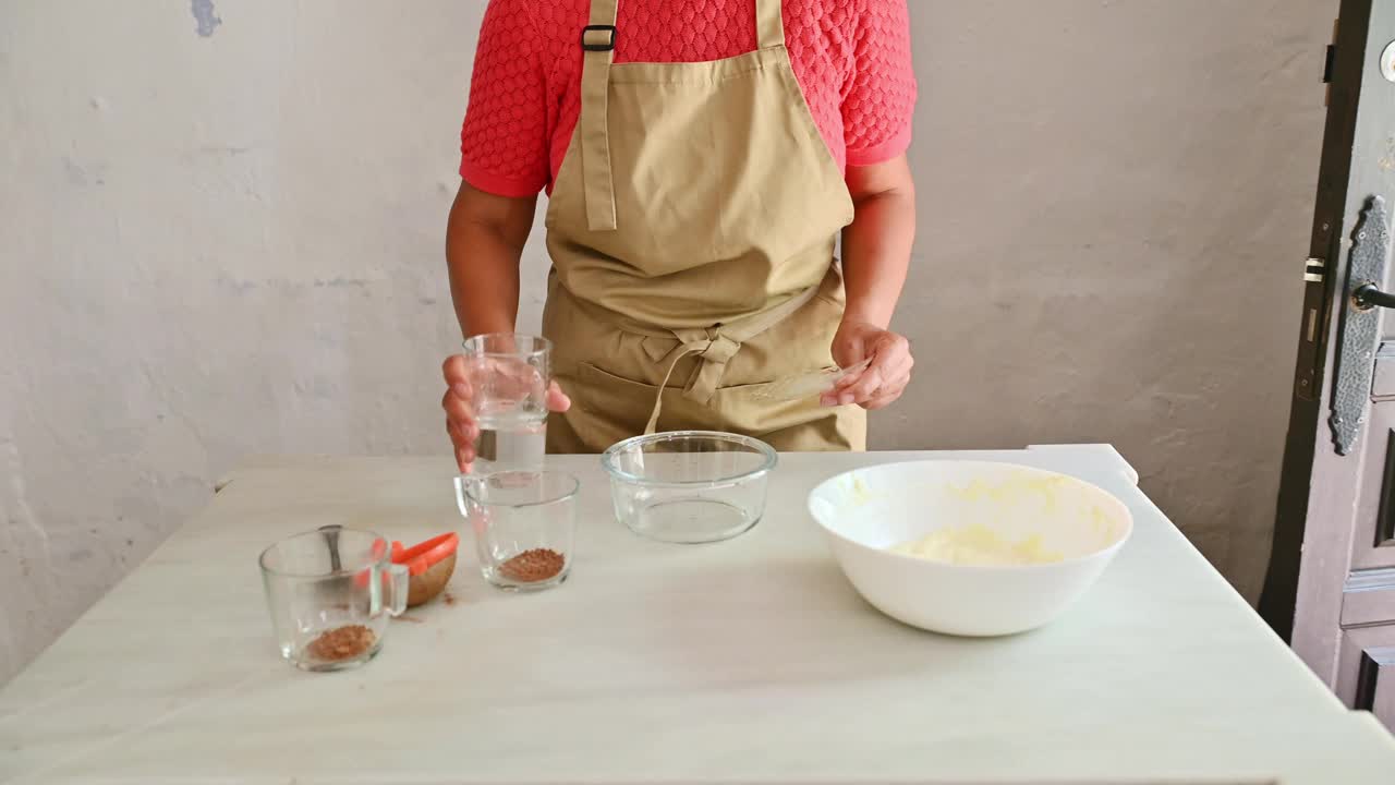 一名妇女在厨房准备烘焙用的食材，她的重点是在碗里混合不同的食材视频素材