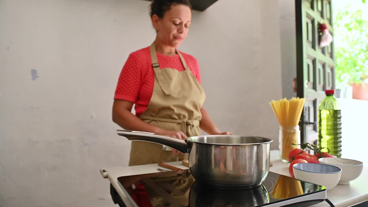 一名妇女在带电磁炉的现代厨房里准备意大利面食视频素材