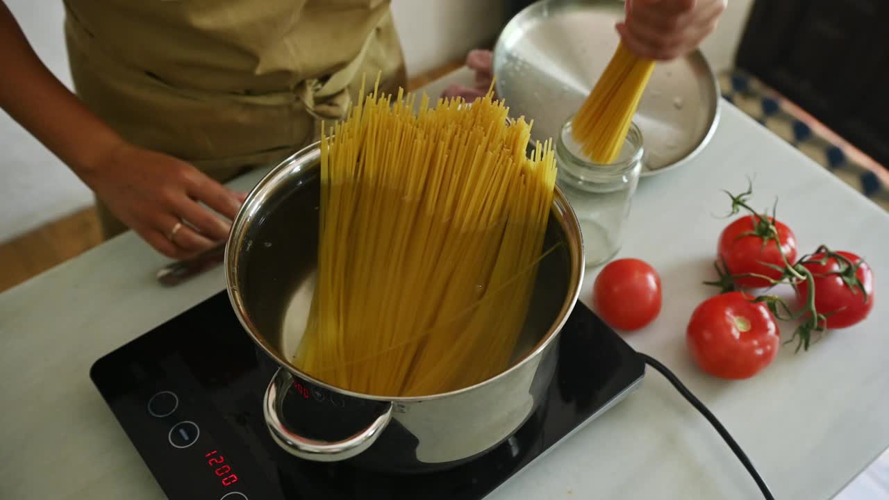 准备意大利面食的人，在家庭厨房里用西红柿烹饪新鲜的意大利面视频素材