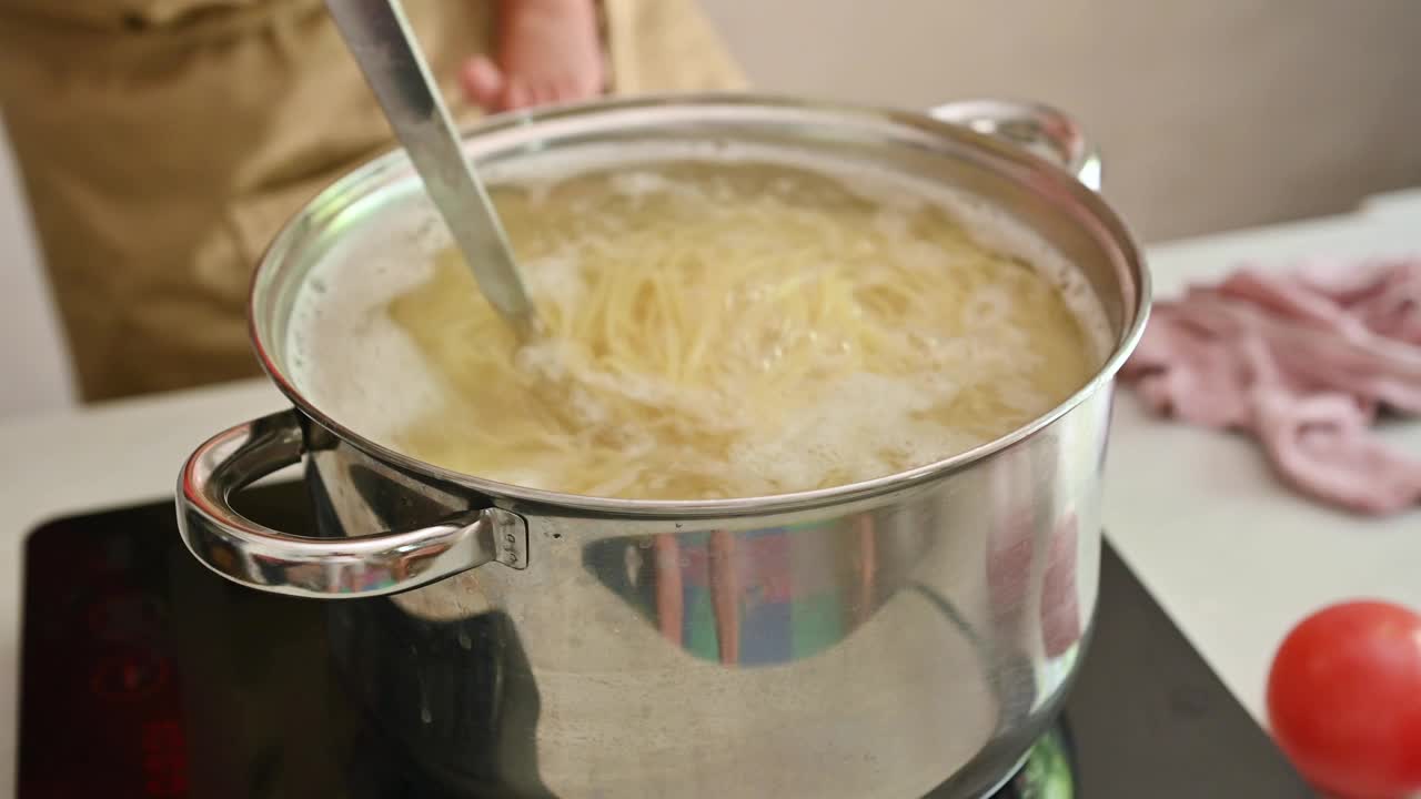 近距离拍摄在炉子上的不锈钢锅里用沸水煮意大利面视频素材