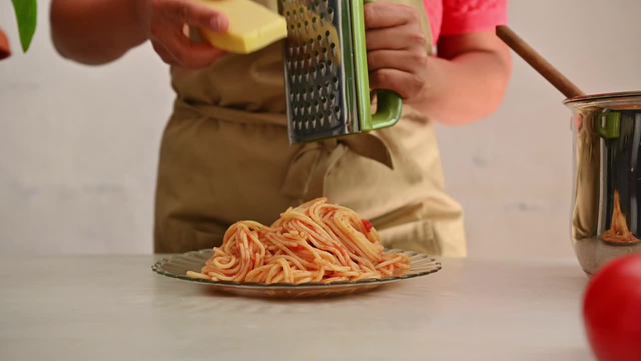 在舒适的厨房里，一个人在一盘新鲜做的意大利面食上磨奶酪视频素材