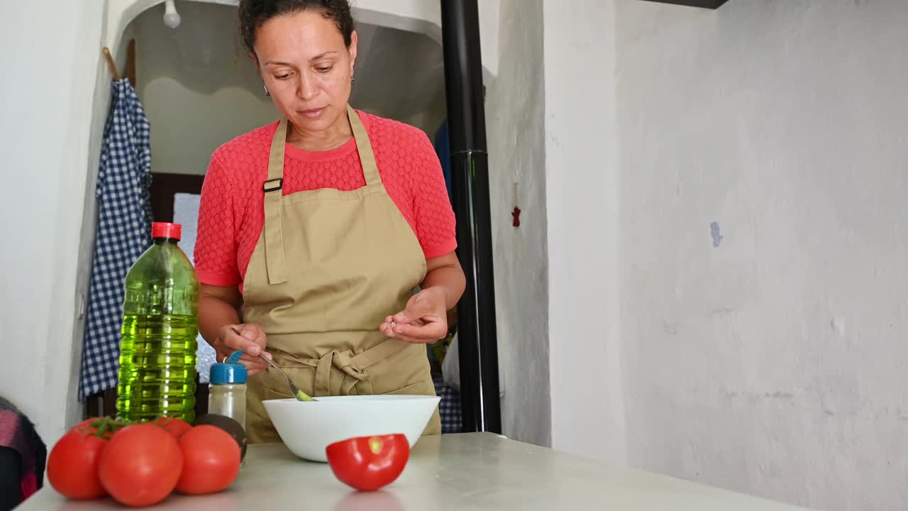 一名妇女在简陋的厨房里用西红柿和橄榄油准备一顿新鲜的饭菜视频素材