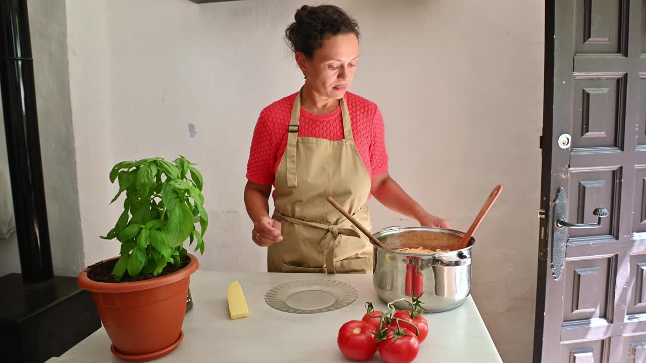 一名妇女在舒适的厨房里用新鲜的食材烹饪传统的意大利面食视频素材