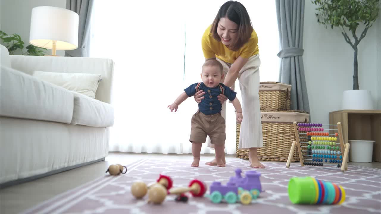 一个小孩子和爷爷在客厅的地板上练习走路视频素材