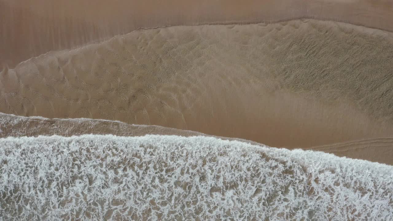 清澈的海浪在沙洲上翻滚，在浅滩上创造出美丽的自然液体图案，白色的海鸥在上面飞翔。视频素材