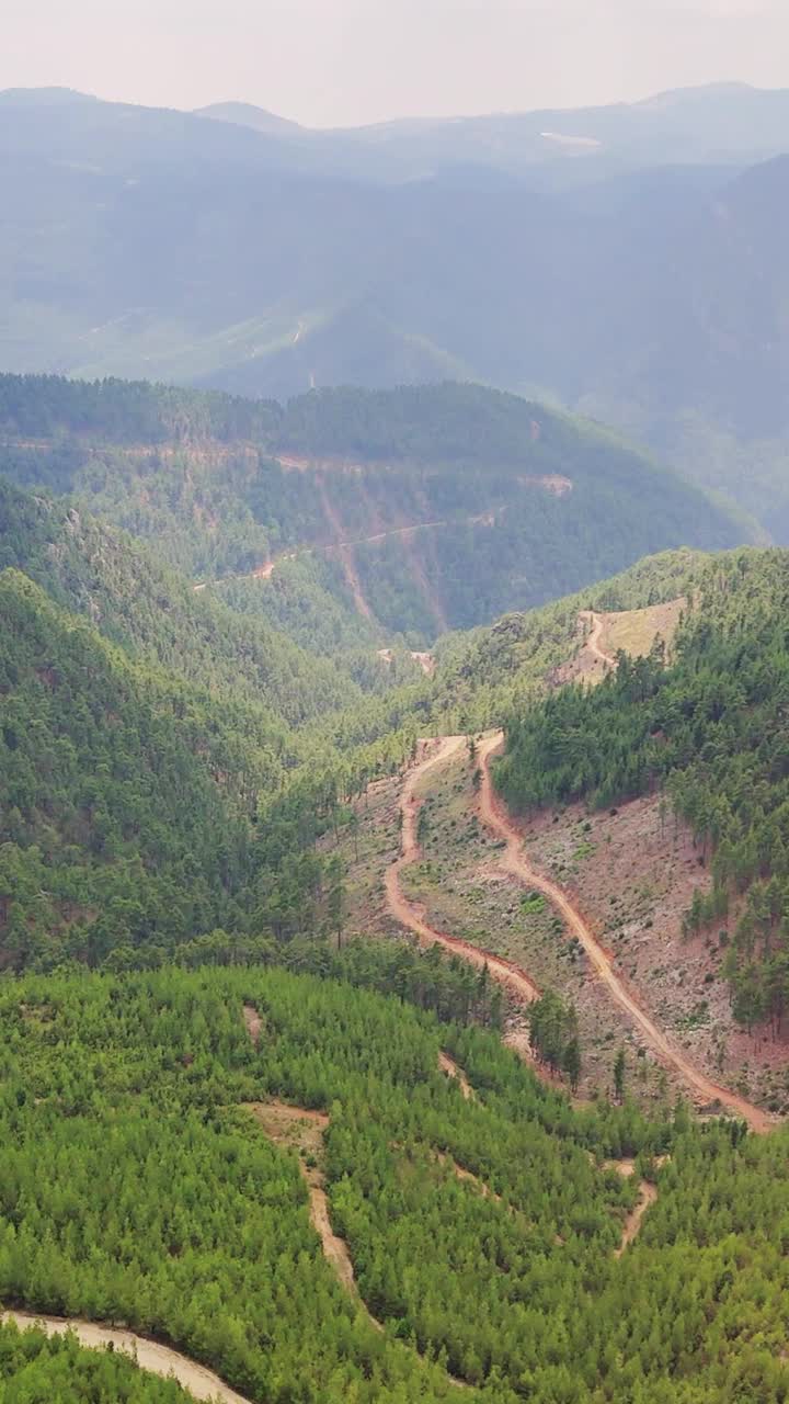 在阳光明媚的日子里，从鸟瞰的角度探索翠绿的山谷和蜿蜒的道路的壮丽景色。适合自然和旅游项目视频素材