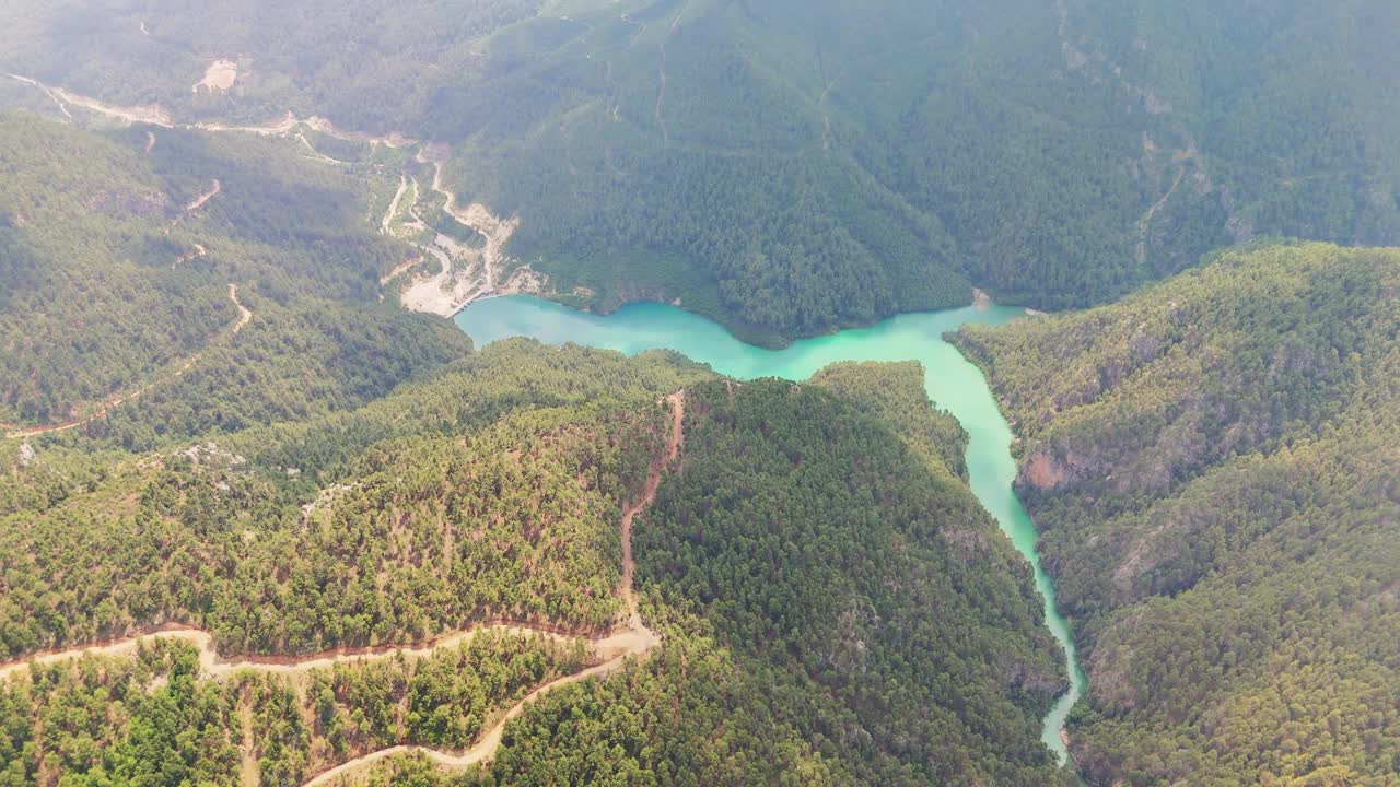 宁静的绿色湖泊坐落在郁郁葱葱的森林山丘，捕捉美丽的水和植被在一个宁静的自然环境视频素材