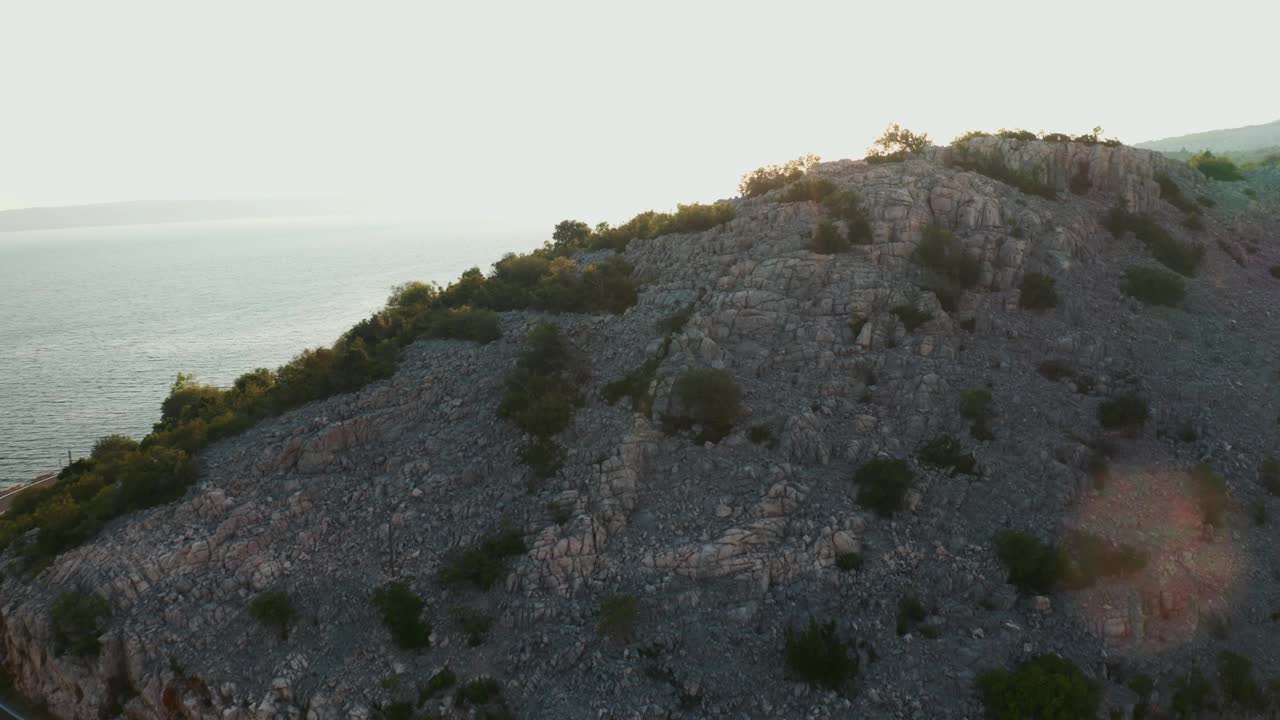 沿着海湾的堤岸附近有稀疏的绿色植物的山脉视频下载