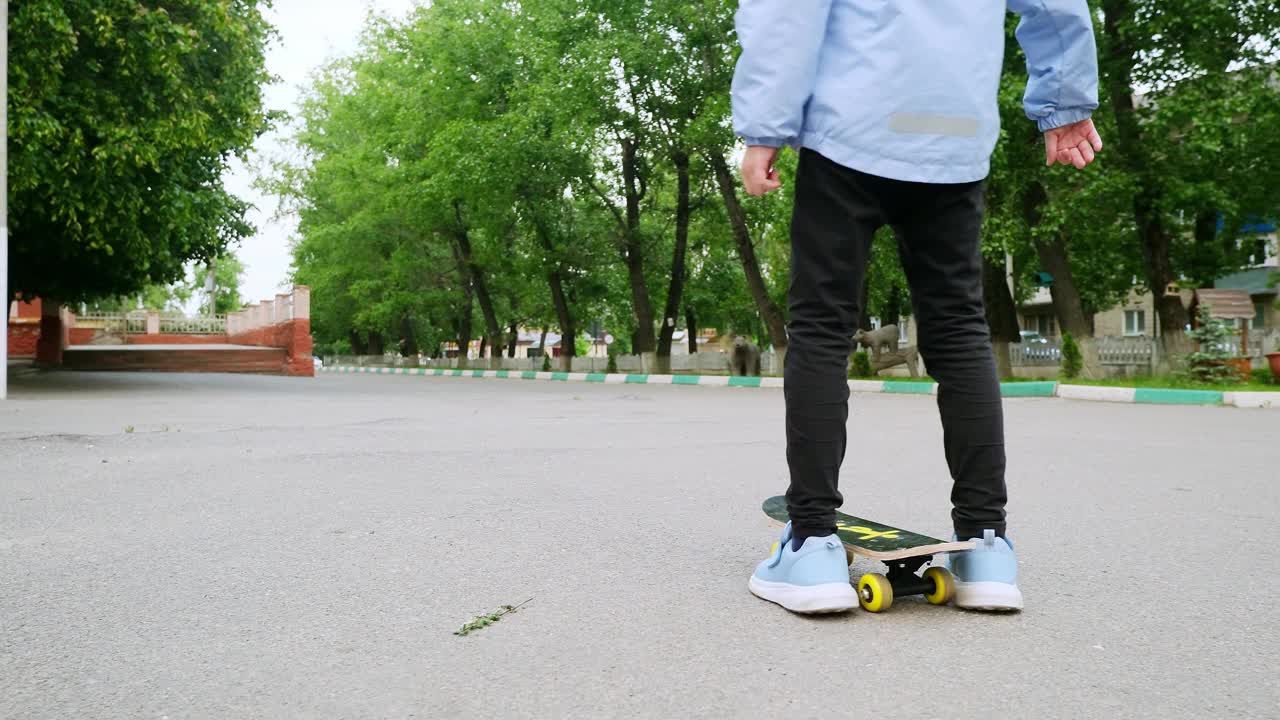 小女孩在柏油路上学习滑板。快乐的女孩在夏天骑滑冰在街上视频素材