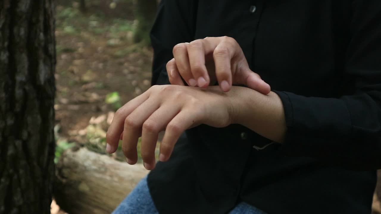 年轻的亚洲女人在公园抓胳膊。真菌感染，湿疹视频下载