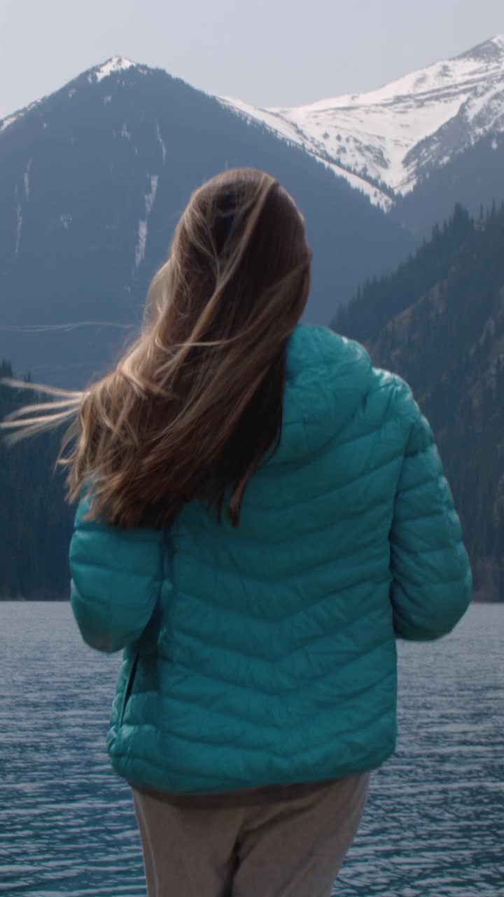 一个徒步旅行的女孩沿着山间湖泊的码头奔跑。女人独自旅行。女性举起双臂视频下载