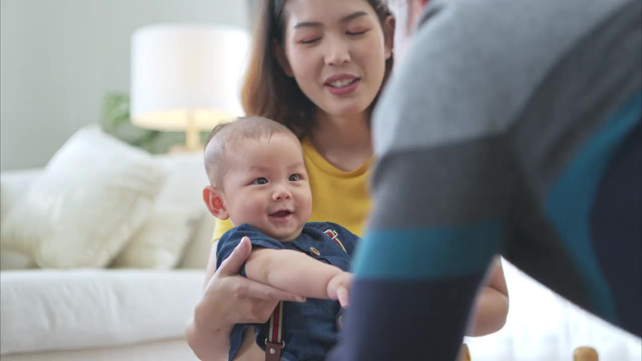 一个小孩子和妈妈、爷爷在客厅的地板上愉快地玩着玩具视频素材