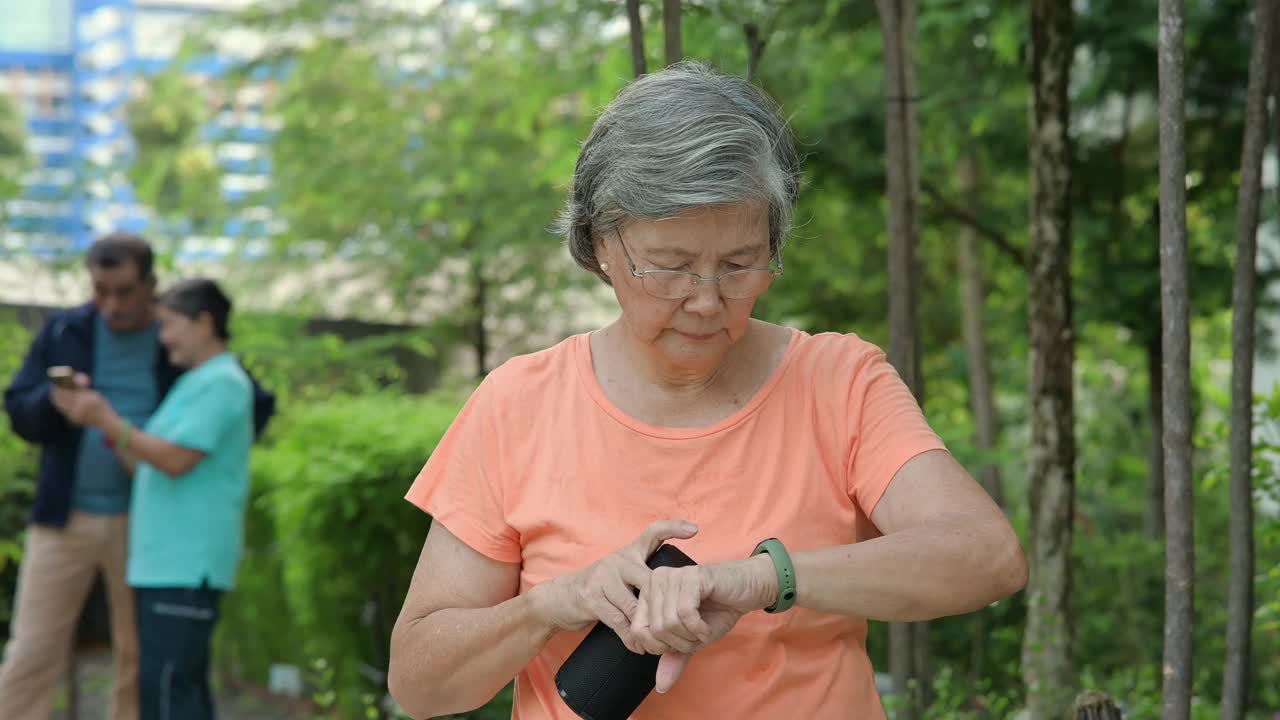 亚洲老年妇女正在学习如何使用手机连接智能扬声器。视频下载