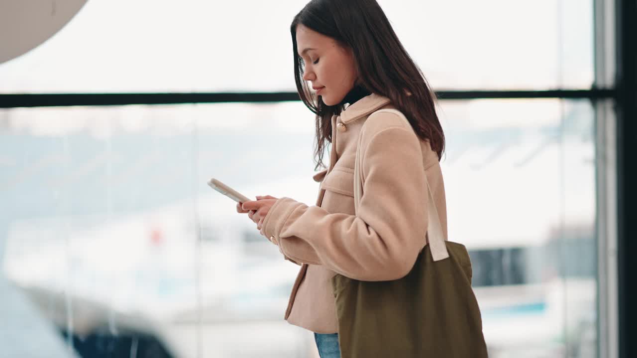 年轻女子在渡轮站窗口用智能手机发短信视频素材