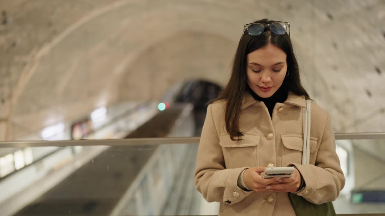 年轻女子在火车站站台使用智能手机视频素材