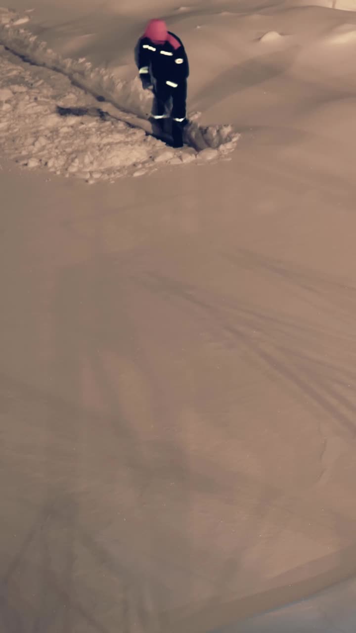 在北极的夜空下，工人在工厂里清理积雪，严酷的寒冷环境强调了极端北方气候下工业劳动的苛刻性质。垂直视频延时视频素材