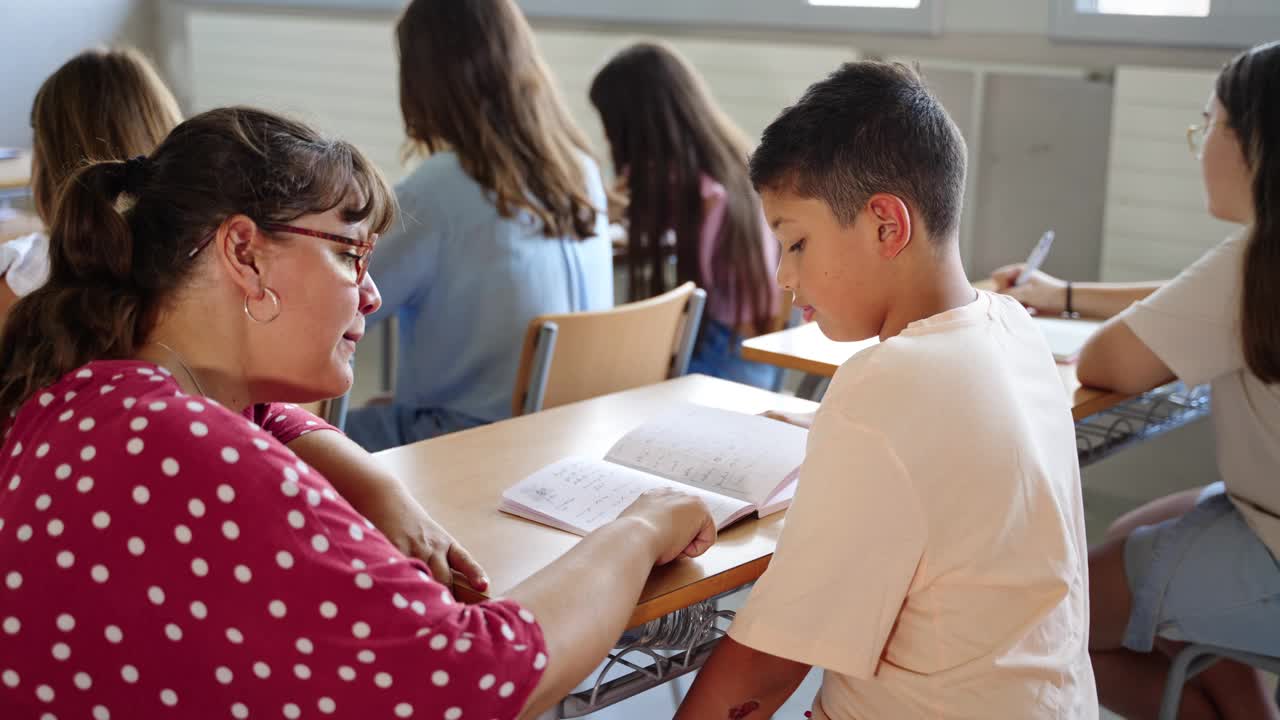 青年教师在小学课堂上帮助西班牙裔学生男孩理解家庭作业视频下载