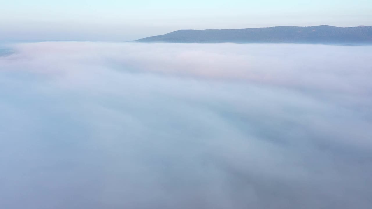 黎明鸟瞰云中露出山脊的景象视频下载