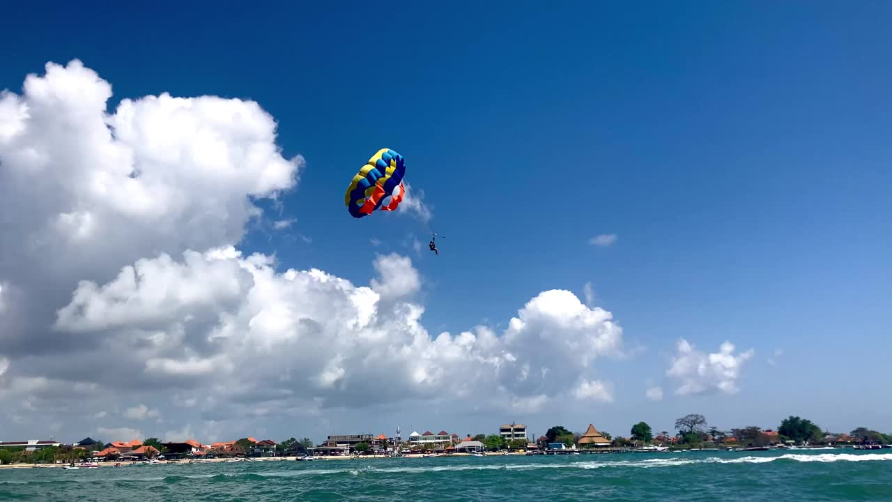 一个游客在海滩上玩伞，夏季水上运动的乐趣视频下载