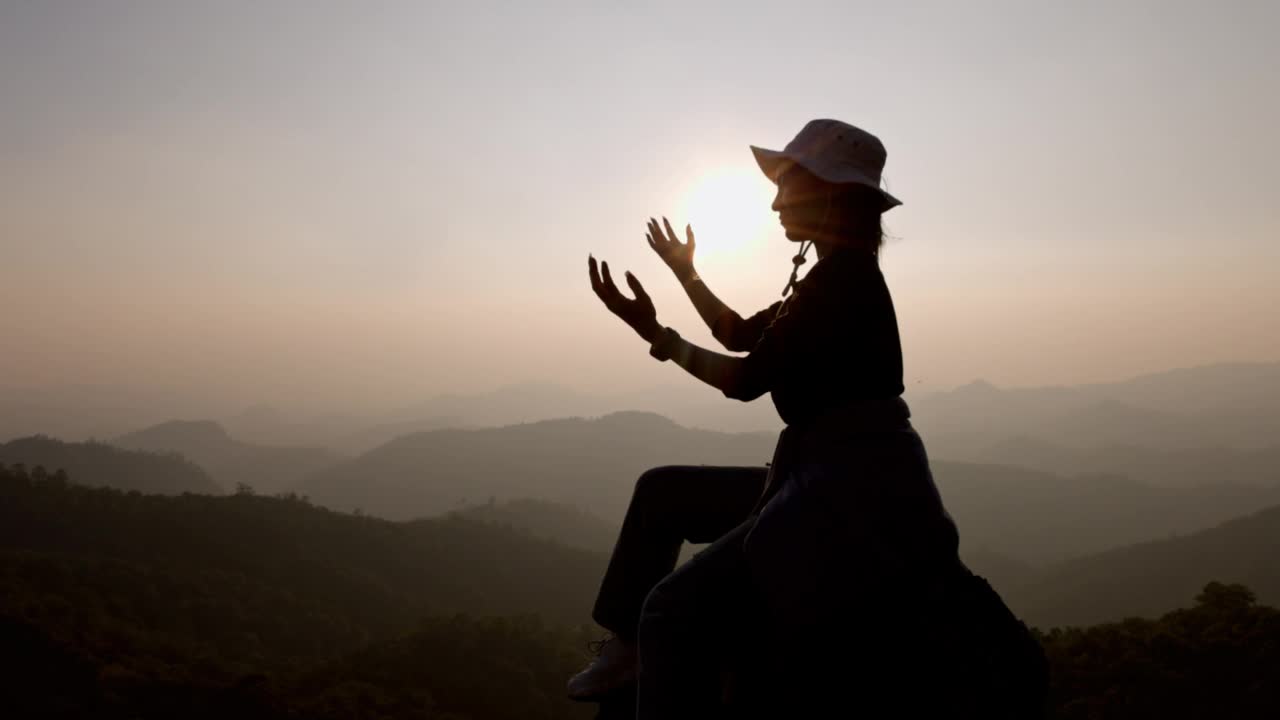 在日出的背景下，女人向上帝祈祷的剪影。基督徒向耶稣基督祈求平静。早晨，人们来到一个安静的地方祈祷。视频下载